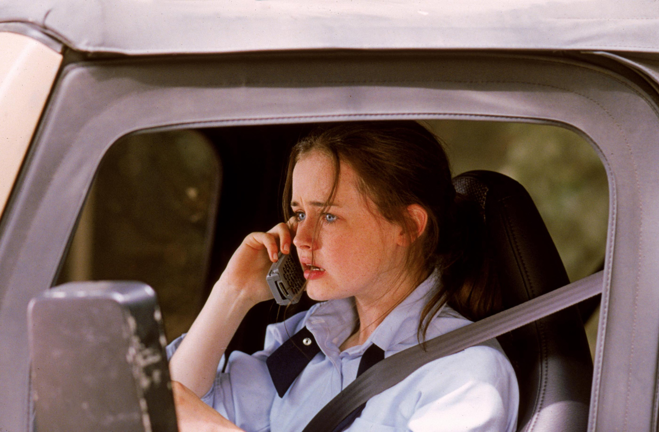 Rory sitting in the driver's seat of her Jeep holding a Motorola Startac to her ear. An expression of worry grips her face.